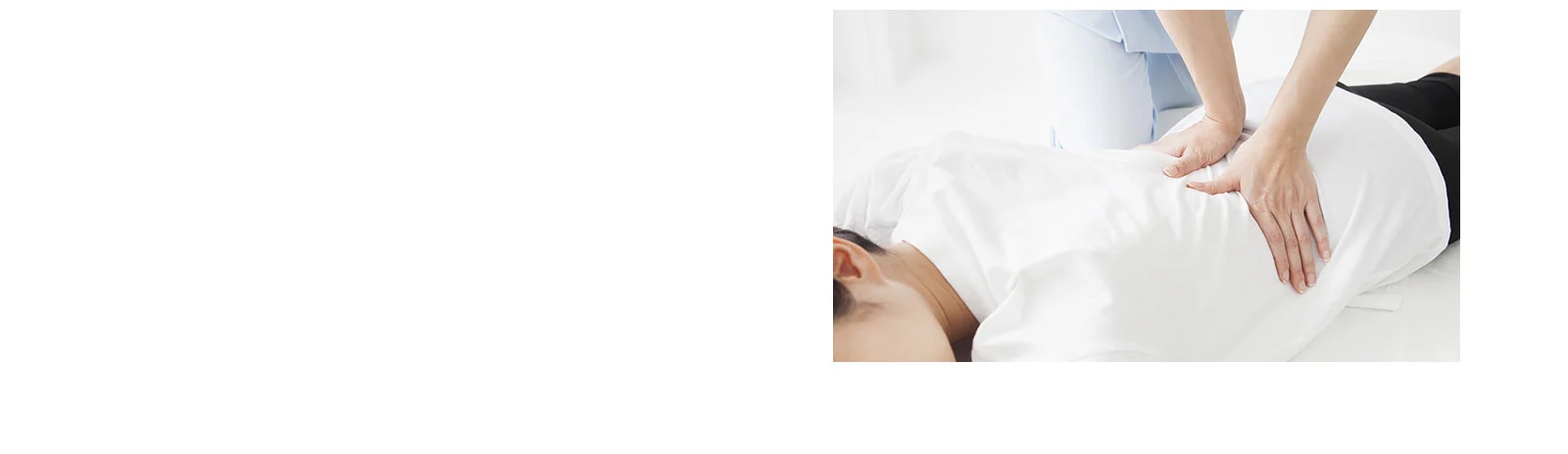 사람이 하얀색 옷을 입고 엎드려 누워 있으며, 다른 사람이 그 위에 손을 올려 마사지를 하고 있습니다. 마사지하는 사람은 하늘색 옷을 입고 있습니다.